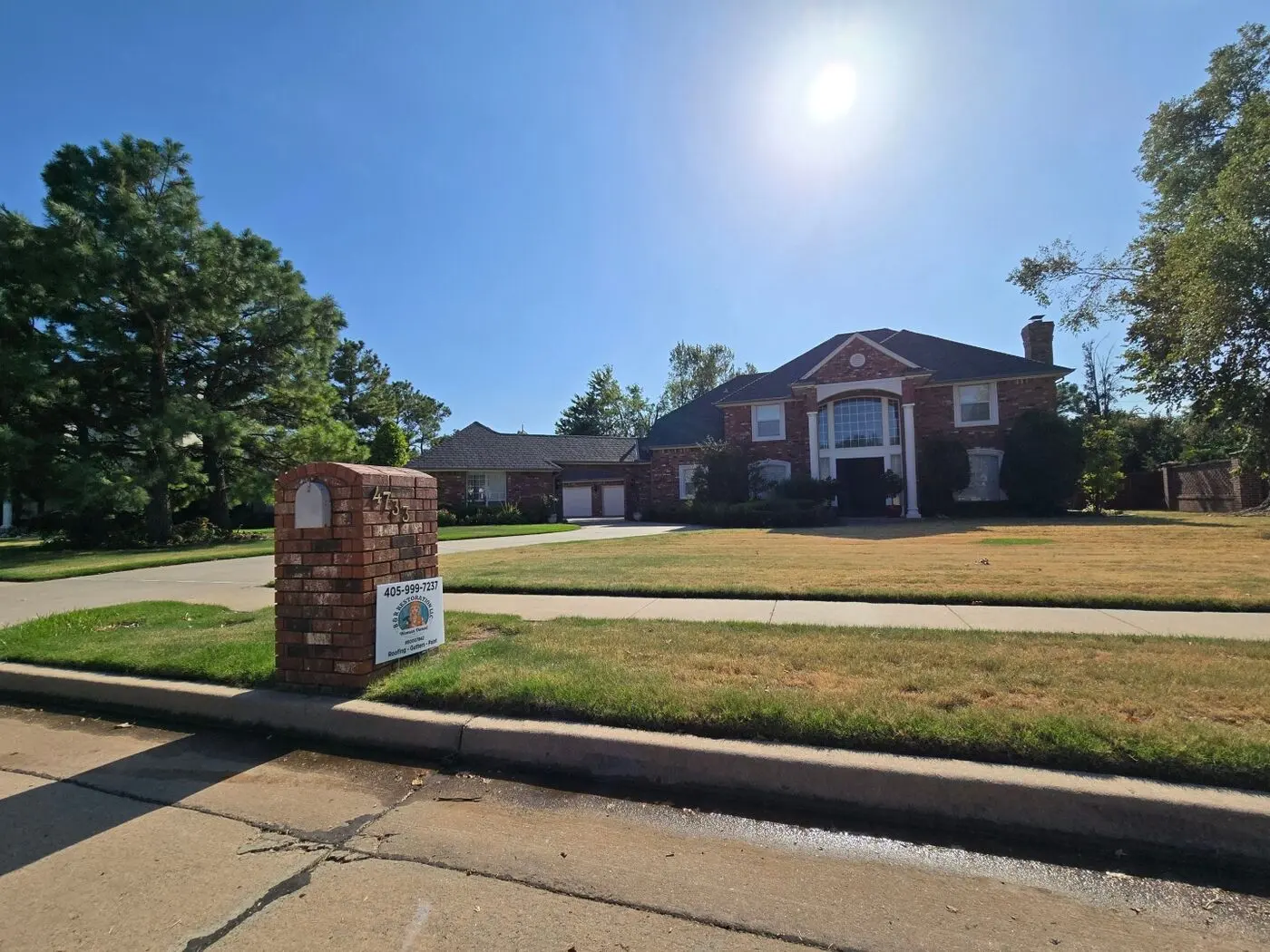 Large red brick estate home with a completed roof restoration and B & R Restoration yard sign